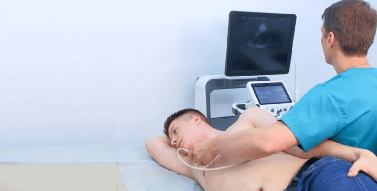 Especialista realizando un ecocardiograma a un paciente recostado